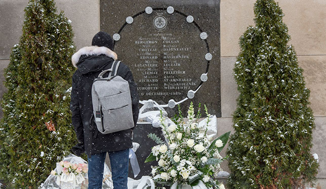 Someone stands in front of a memorial for victims of the Polytechnique massacre.